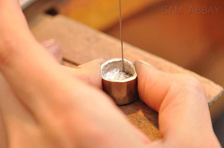 Sawing out the center of a coin to make a ring